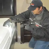 Bed bug inspection technician checking a mattress and bed frame for signs of infestation in Glendale, AZ