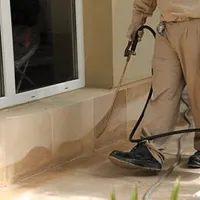 General pest control technician spraying exterior perimeter around a home in Glendale, AZ