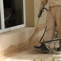 General pest control technician spraying exterior perimeter around a home in Glendale, AZ