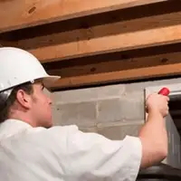 Termite inspection technician checking a basement wall and framing for termite activity in Glendale, AZ